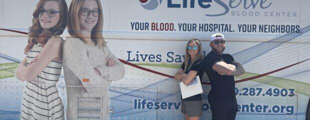 Austin Fuller and Jess Jager standing beside the LifeServe Bloodmobile during C21 Day of Giving